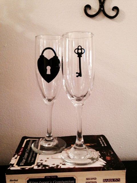 a pair of simple flutes decorated with a lock and a key is a cool and fun idea for a wedding, accent the couple's glasses this way easily yourself