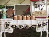 a vintage-inspired popcorn bar with an elegant table, a paper garland, a mirror and popcorn machine plus paper bags