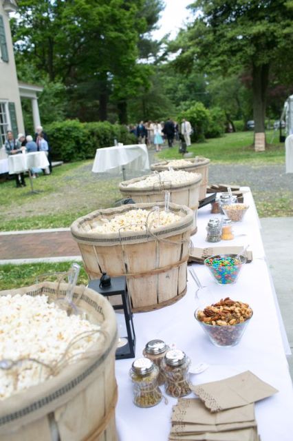 a cozy popcorn bar with wooden baskets with popcorn, lanterns, condiments and sprinkles