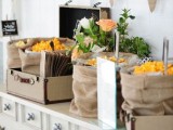 a rustic popcorn bar done with a vintage console table, suitcases and burlap sacks withh popcorn