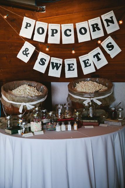 a relaxed popcorn bar with buckets with popcorn, sprinkles and sweets and letter banners