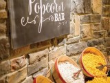 a simple and stylish popcorn bar with wooden baskets with various kinds of popcorn and a chalkboard sign