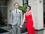 a chic dressed couple – a grey three-piece suit, a grey tie, red shoes and a short red lace dress and red shoes