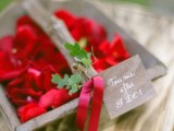 a wooden basket with red blooms, a red ribbona nd greenery on it is great for a little flower girl at your wedding