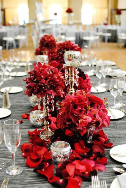 a shiny grey tablecloth and lush red florals plus crystals and mercury glass candleholders