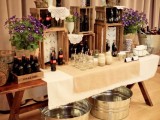 a relaxed rustic wedding drink bar of a trestle table, some bright blooms and shelves composed of simple wooden crates is a lovely solution to rock