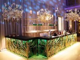 a refined and chic weddign drink bar of a beautiful stand with green and gold detailing, flower trees and lots of light is a lovely idea
