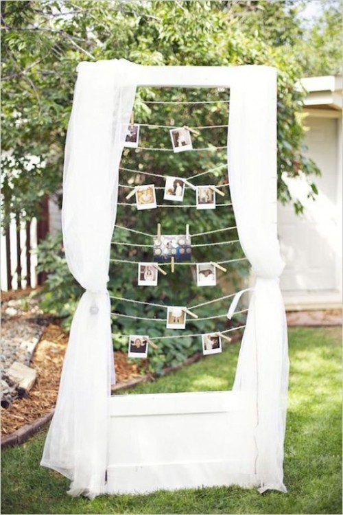 a cute wedding decoration of a frame with curtains and Polaroids hanging on the ropes