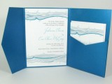 a blue, aqua and white beach wedding invitation suite in an envelope, with whale inspired prints that are all pretty and bold