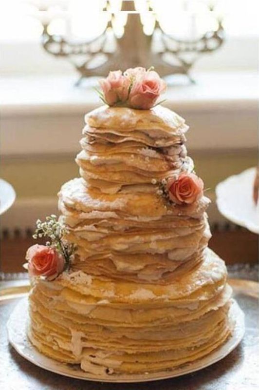 A crepe wedding cake with cream and pink blooms is a gorgeous and delicious solution for your wedding