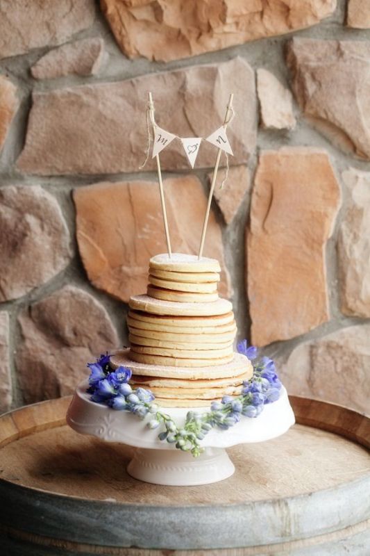 A classy pancake wedding cake with caramel in between, with fresh blooms and a bunting cake topper for a rustic wedding