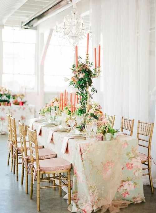 a sophisticated wedding tablescape with a floral print tablecloth, neutral blooms, greenery and coral candles is amazing