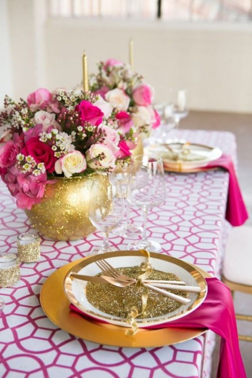 a bold chic and glam wedding tablescape with a bright printed tablecloth and matching berry-hued napkins, gold tableware, cutlery and vases with fuchsia and white blooms