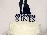 a white textural wedding cake topped with a black silhouette and letter cake topper is a stylish and cool idea