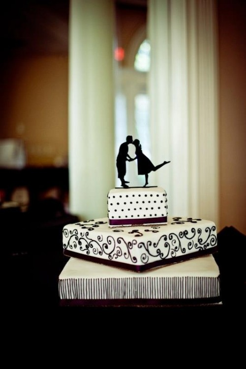 a black and white square wedding cake with mismatching tiers and a black couple's silhouette kissing on top is a fun and cool solution for a wedding