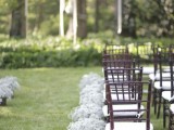 a chic backyard wedding ceremony space with ribbons and baby’s breath balls hanging froma  tree, baby’s breath in pots along the wedding aisle