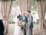 a cozy backyard rustic wedding space with burlap, greenery, lights over the space and burlap rugs