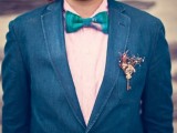 a navy suit, a pink printed shirt, a bright turquoise bow tie and a steampunk boutonniere with a vintage key