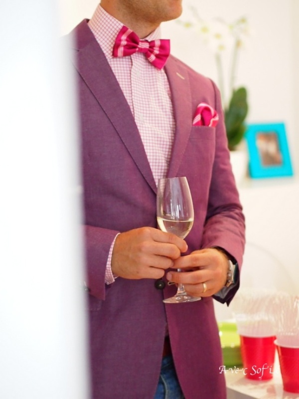 a purple suit, a printed pink shirt, a brigth pink bow tie and a matching handkerchief