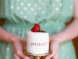 a tiny individual wedding cake with a fresh berry on top and a name written on it is a very chic and cute idea