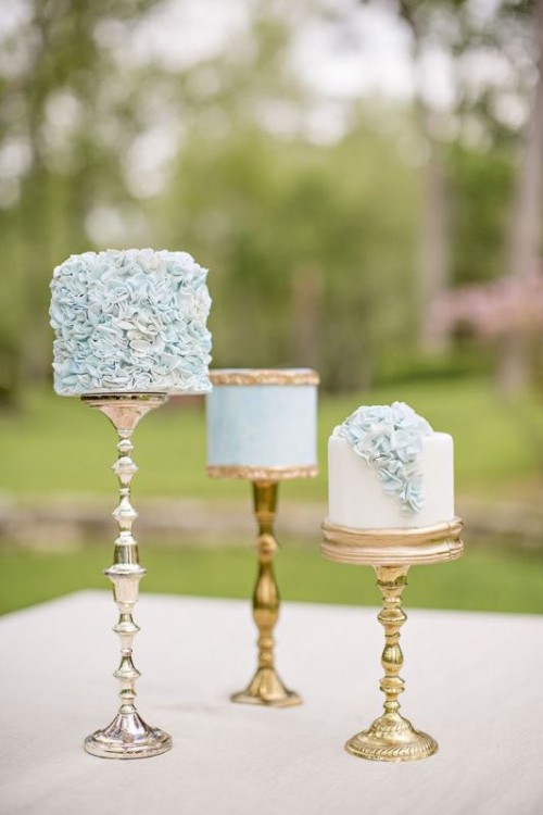 an assorment of blue mini cakes on gold stands, with ruffles and gold detailing for a romantic and refined wedding