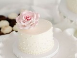 a white mini wedding cake decorated with edible pearls and a blush sugar rose on top is a stylish idea