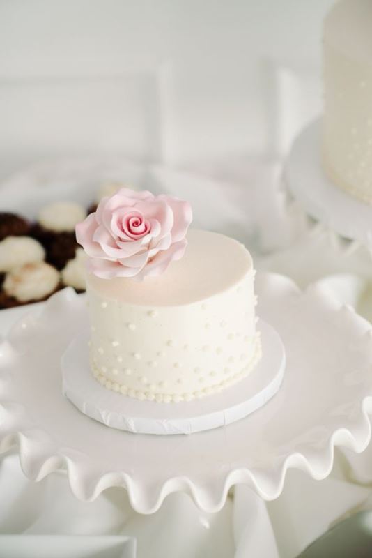 A white mini wedding cake decorated with edible pearls and a blush sugar rose on top is a stylish idea