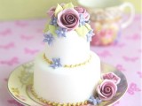 an individual wedding cake decorated with gold beads, blue, green and mauve sugar flowers