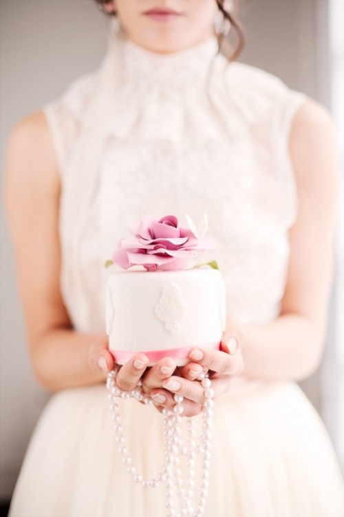 a white lace individual cake with a pink stripe and a pink sugar bloom on top is a gorgeous dessert