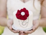 an individual wedding cake decorated with silver patterns and a single burgundy bloom for a vintage wedding