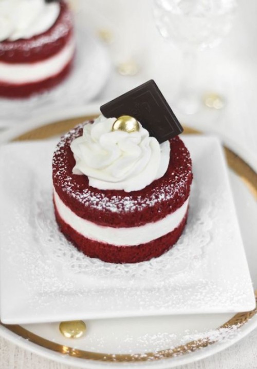 a red velvet individual wedding cake with whipped cream, a shiny bead and some chocolate on top