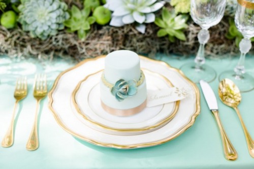 an individual mint-colored wedding cake with copper stripes and a sugar succulent is adorable