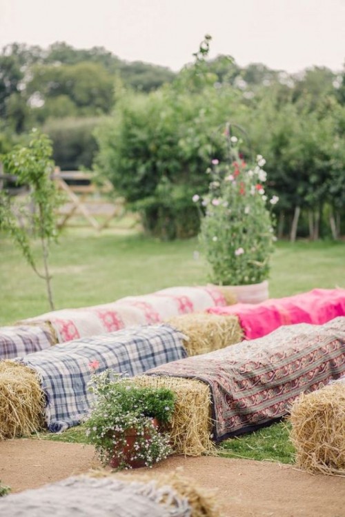 hay stacks covered with plaid and bold blankets will be a nice idea for a rustic wedding, they will add a real rustic feel to the ceremony space