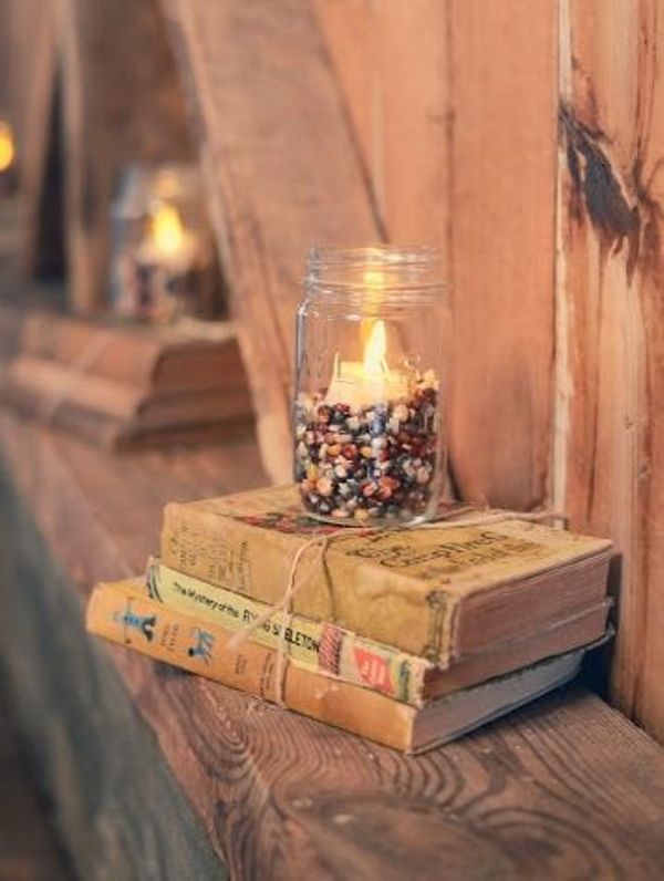 a book stack with a mason jar with corn and a candle are a cool decoration for a rustic vintage wedding
