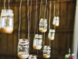 a branch with suspended mason jars with gold glitter will be a lovely decoration for a rustic wedding