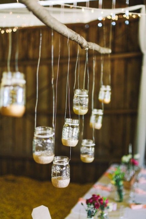 a branch with suspended mason jars with gold glitter will be a lovely decoration for a rustic wedding