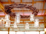 a wedding chandelier of a vine wreath and hanging mason jars with candles is a cool decoration for a rustic wedding