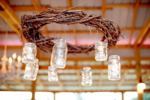 a wedding chandelier of a vine wreath and hanging mason jars with candles is a cool decoration for a rustic wedding