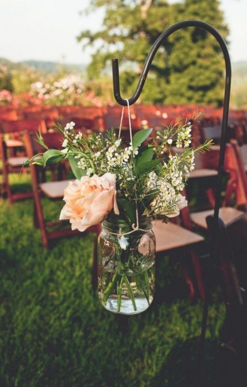 a rustic wedding aisle decorated with a mason jar with pink and white blooms and greenery is a cool decor idea for a rustic wedding