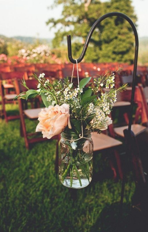 a rustic wedding aisle decorated with a mason jar with pink and white blooms and greenery is a cool decor idea for a rustic wedding