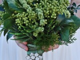 a textural wedding bouquet with large leaves and some berries and an embellished bouquet handle for a cool look