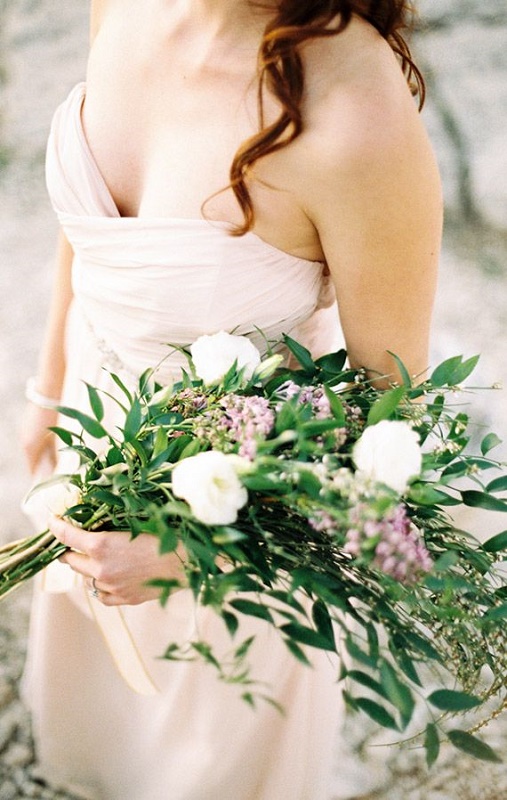 A greenery wedding bouquet with a catchy shape dotted with white and pink flowers is ideal for spring