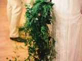 a veyr lush cascading greenery wedding bouquet with lots of various types of greenery going down to the floor