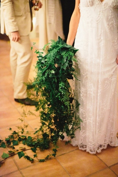 a veyr lush cascading greenery wedding bouquet with lots of various types of greenery going down to the floor