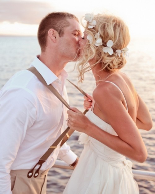 a messy and wavy low updo with locks down and with some fresh tropical blooms is a lovely idea for a beach wedding