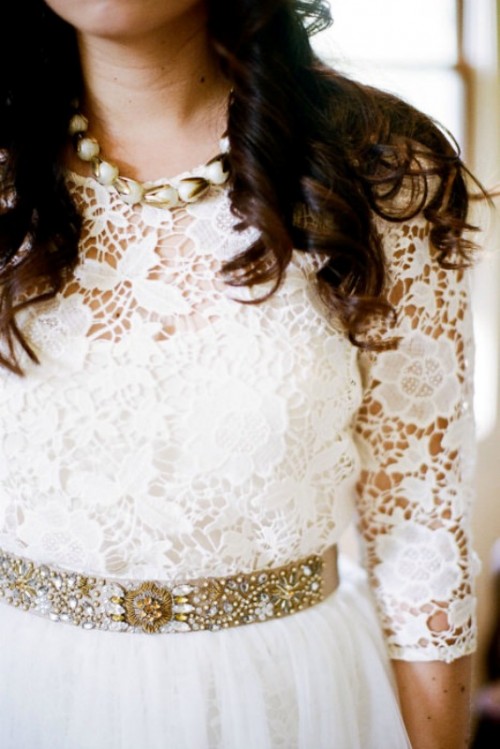 a gold and clear crystal wedding belt is a perfect pair for a chic boho lace wedding dress that the bride is wearing