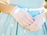 a blue polka dot retro wedding dress with a pleated skirt, white sheer gloves and a thin white belt with a silver buckle