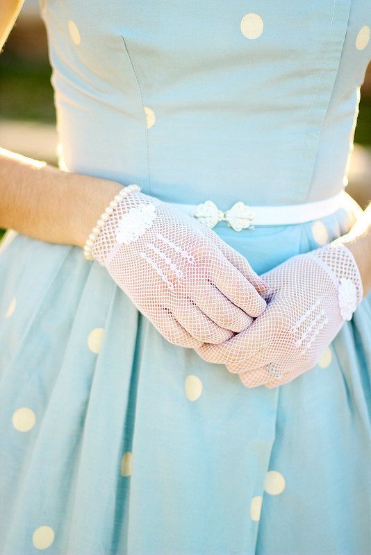 a blue polka dot retro wedding dress with a pleated skirt, white sheer gloves and a thin white belt with a silver buckle