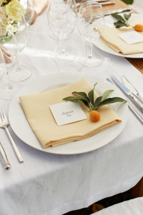 an elegant wedding place setting with white porcelain, a neutral napkin and silver cutlery marked with a little kumquat is wow