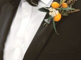 a bright wedding boutonniere of white blooms, greenery and kumquats is a bold and pretty accessory that will refresh your look